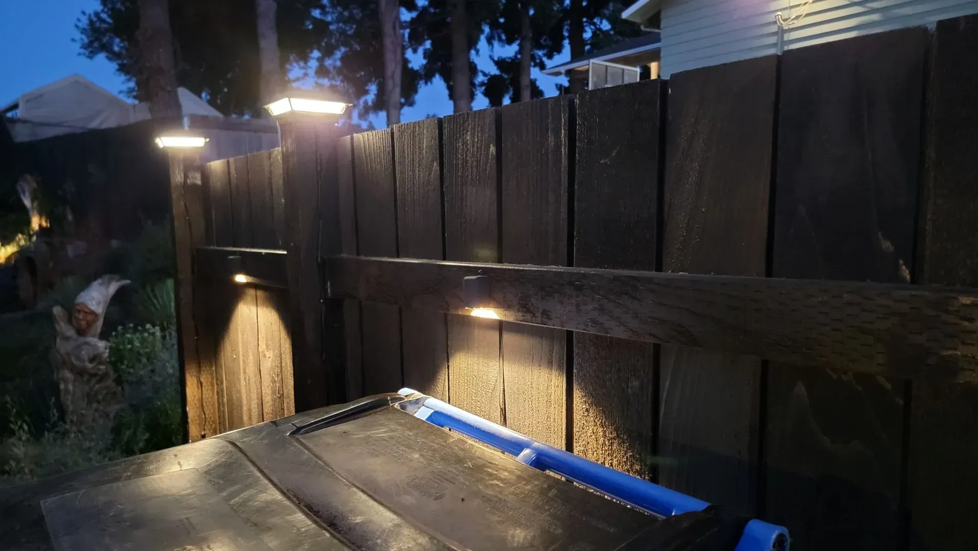 Dark wooden fence illuminated by several lights at night.