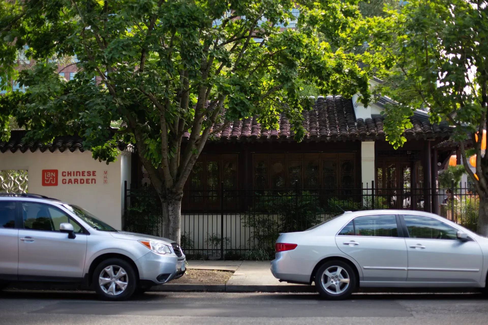A silver SUV and sedan parked in front of a Chinese restaurant with a red sign and a tiled roof.