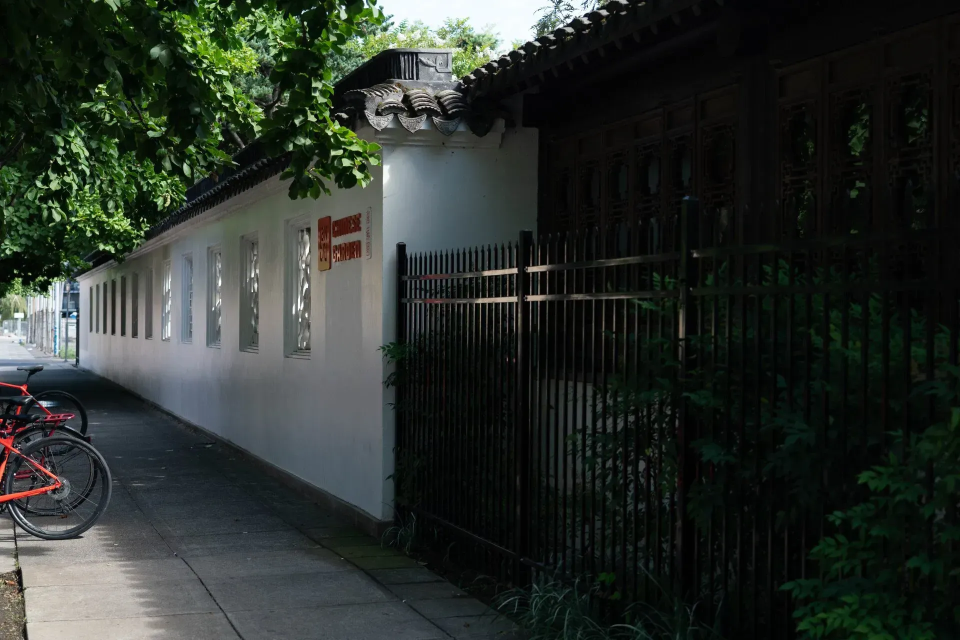 A long, white wall with narrow windows and a black metal fence. 