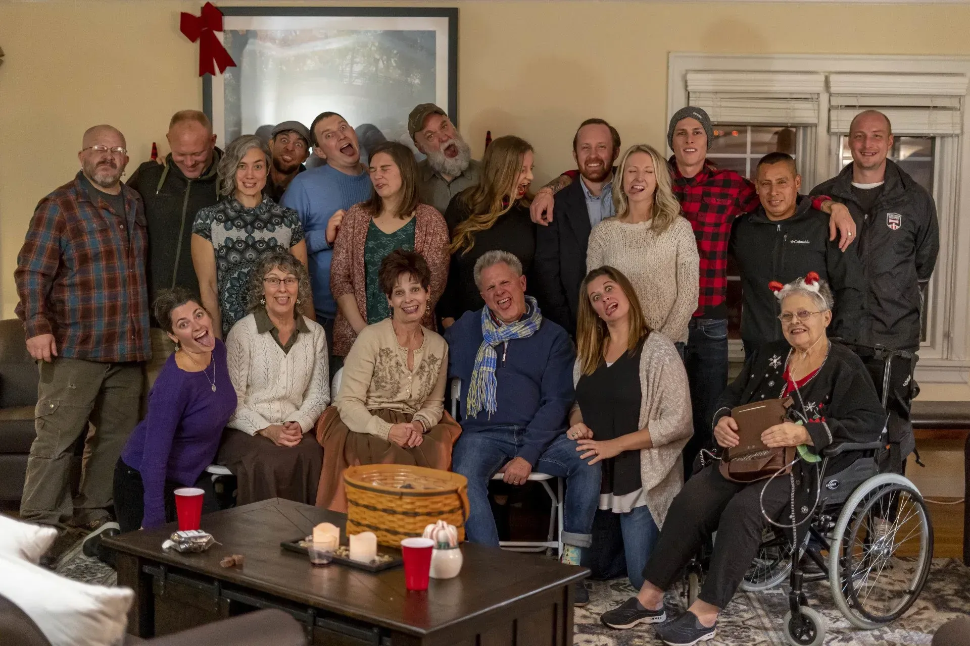 Group of people smiling and posing for a photo indoors, some with silly faces.