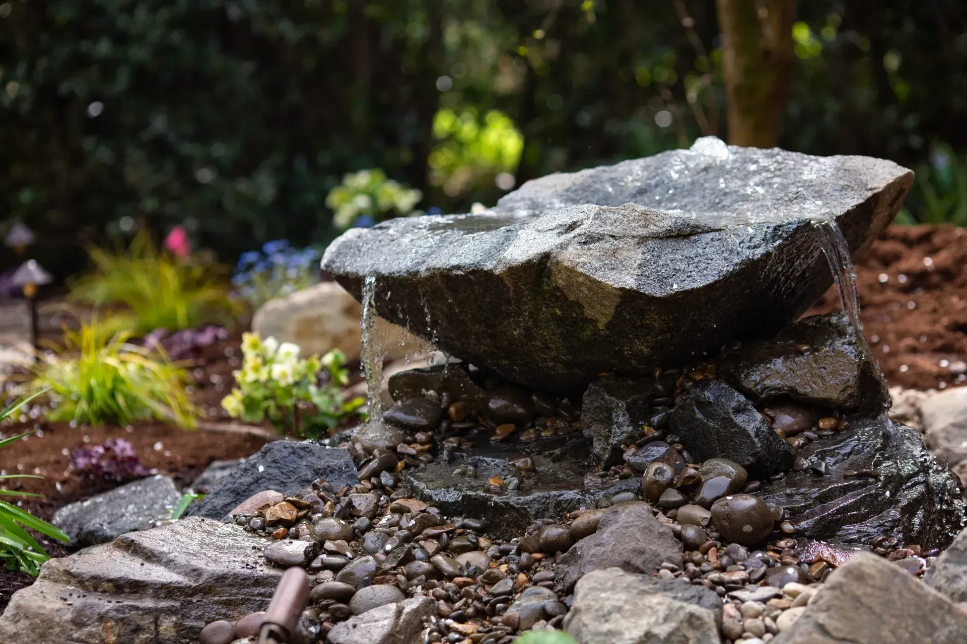 A rock water fountain in a garden.