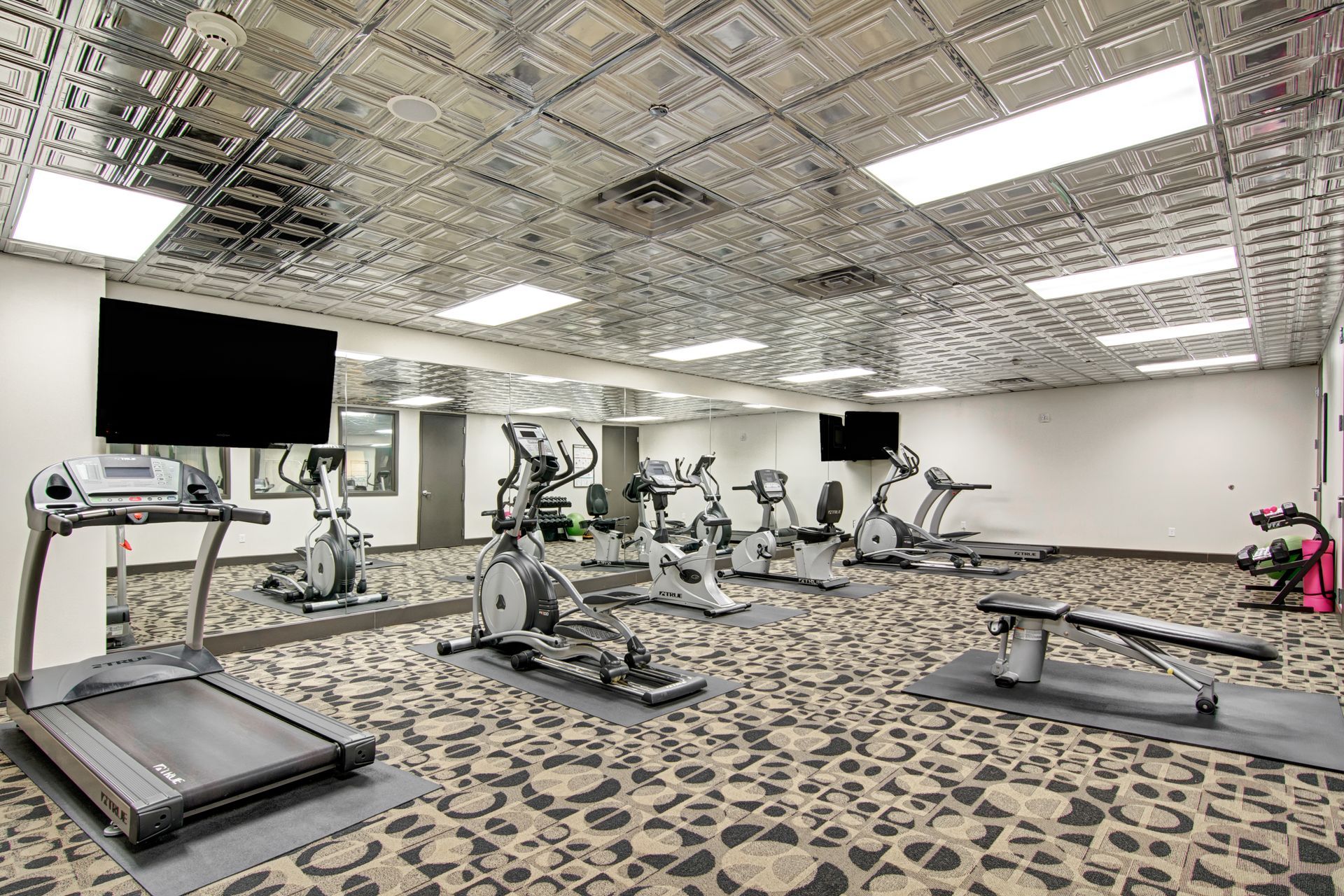 A large gym with a lot of exercise equipment and a flat screen tv.
