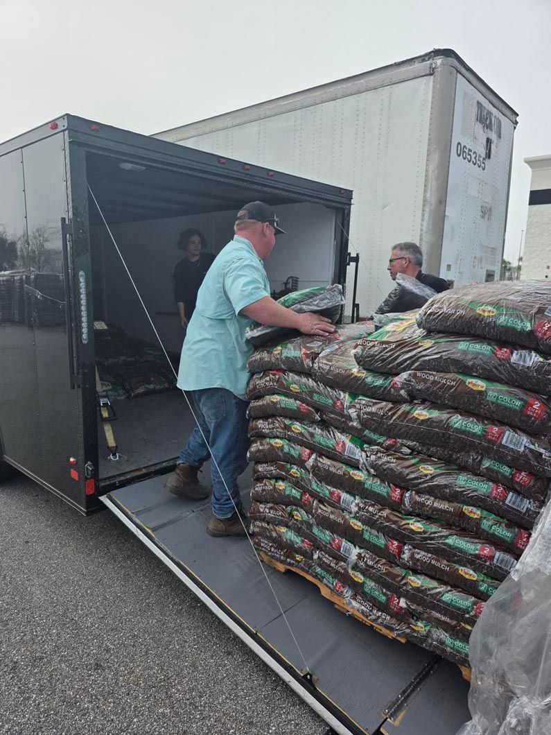 A man is loading bags of dirt into a trailer.