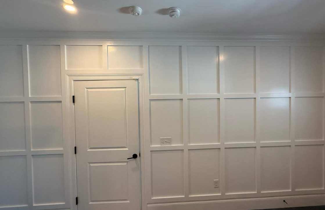 White paneled wall with a door and molding.