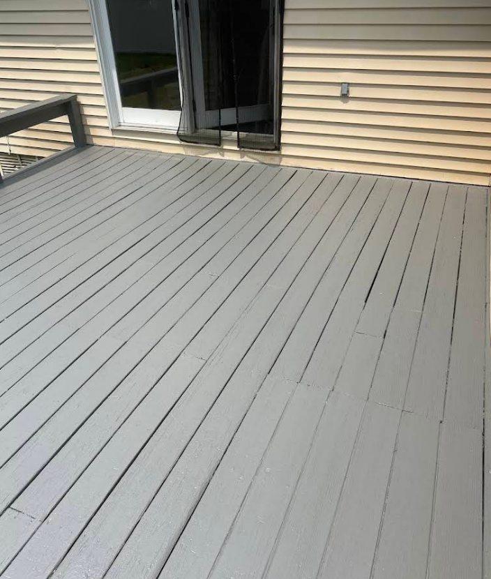 Grey painted wooden deck against a light yellow house with glass door.
