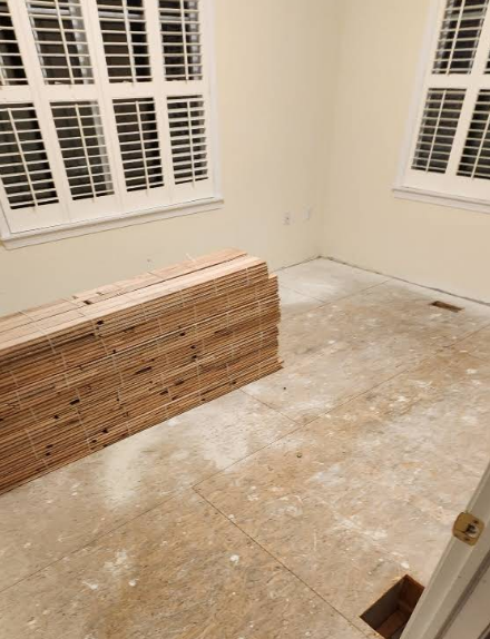 Stack of wood flooring in room with windows and blank walls.