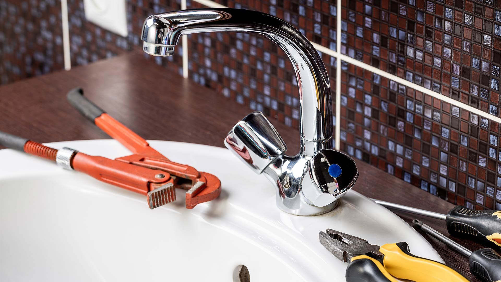 A bathroom sink with a faucet and tools on it.