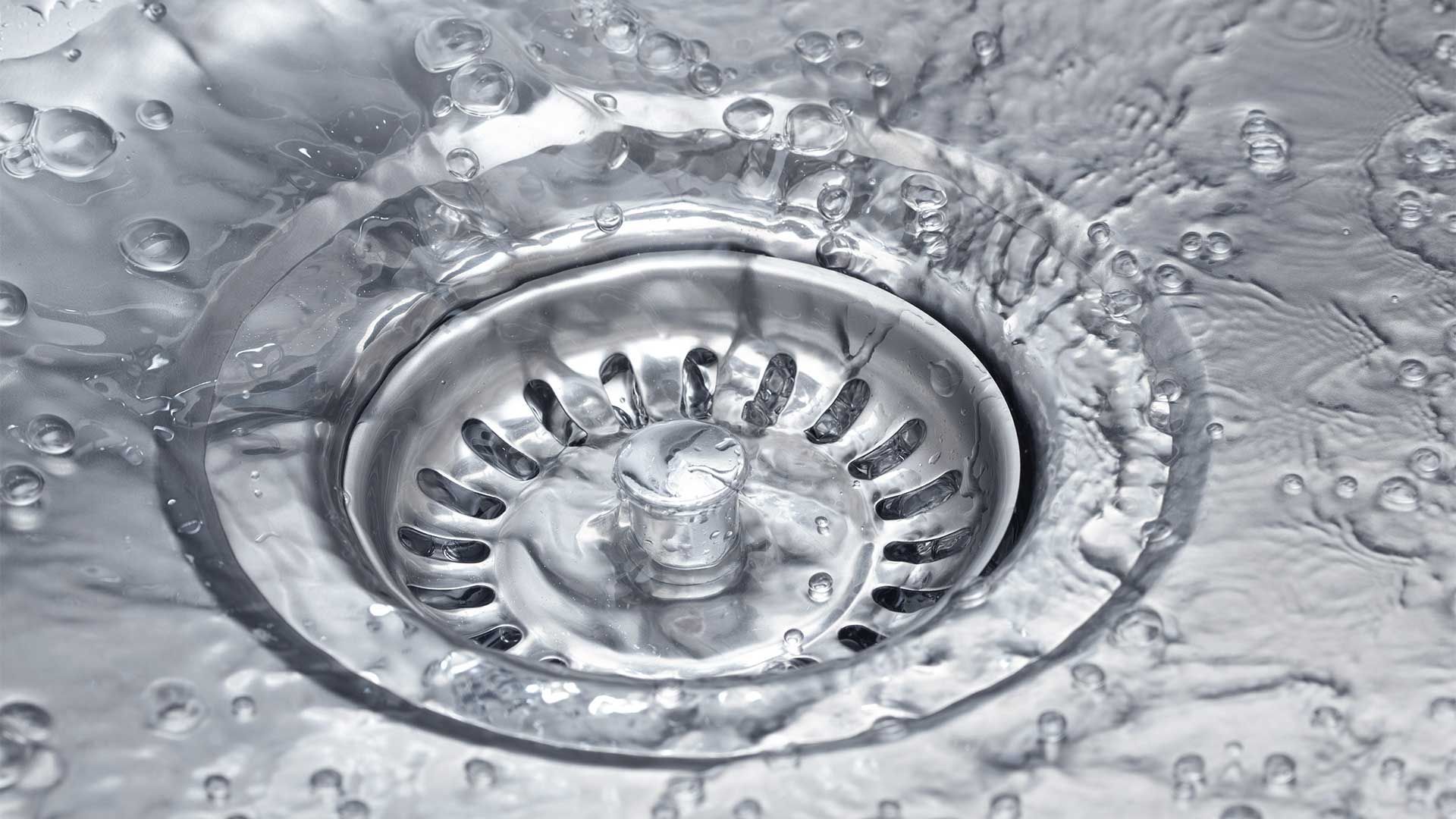 A close up of a sink drain with water coming out of it.