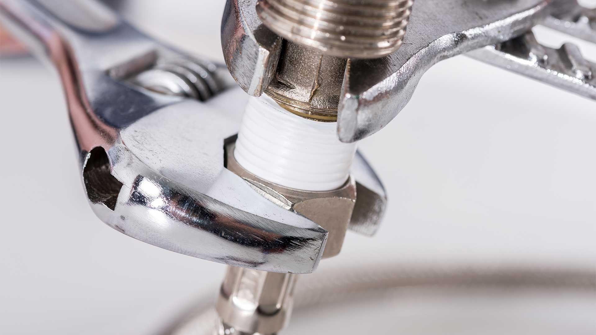 A wrench is being used to fix a faucet.