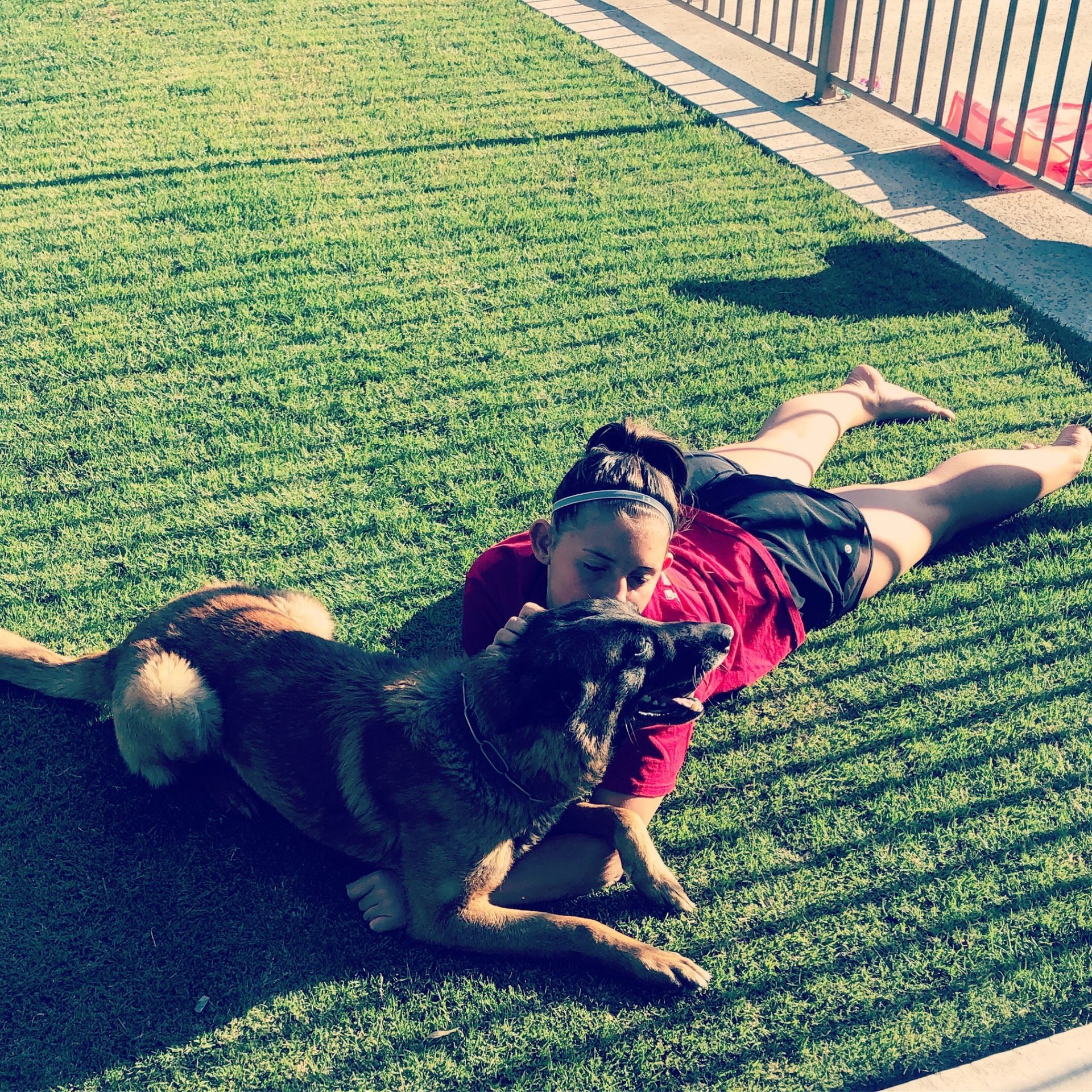 A woman is laying on the grass with a dog