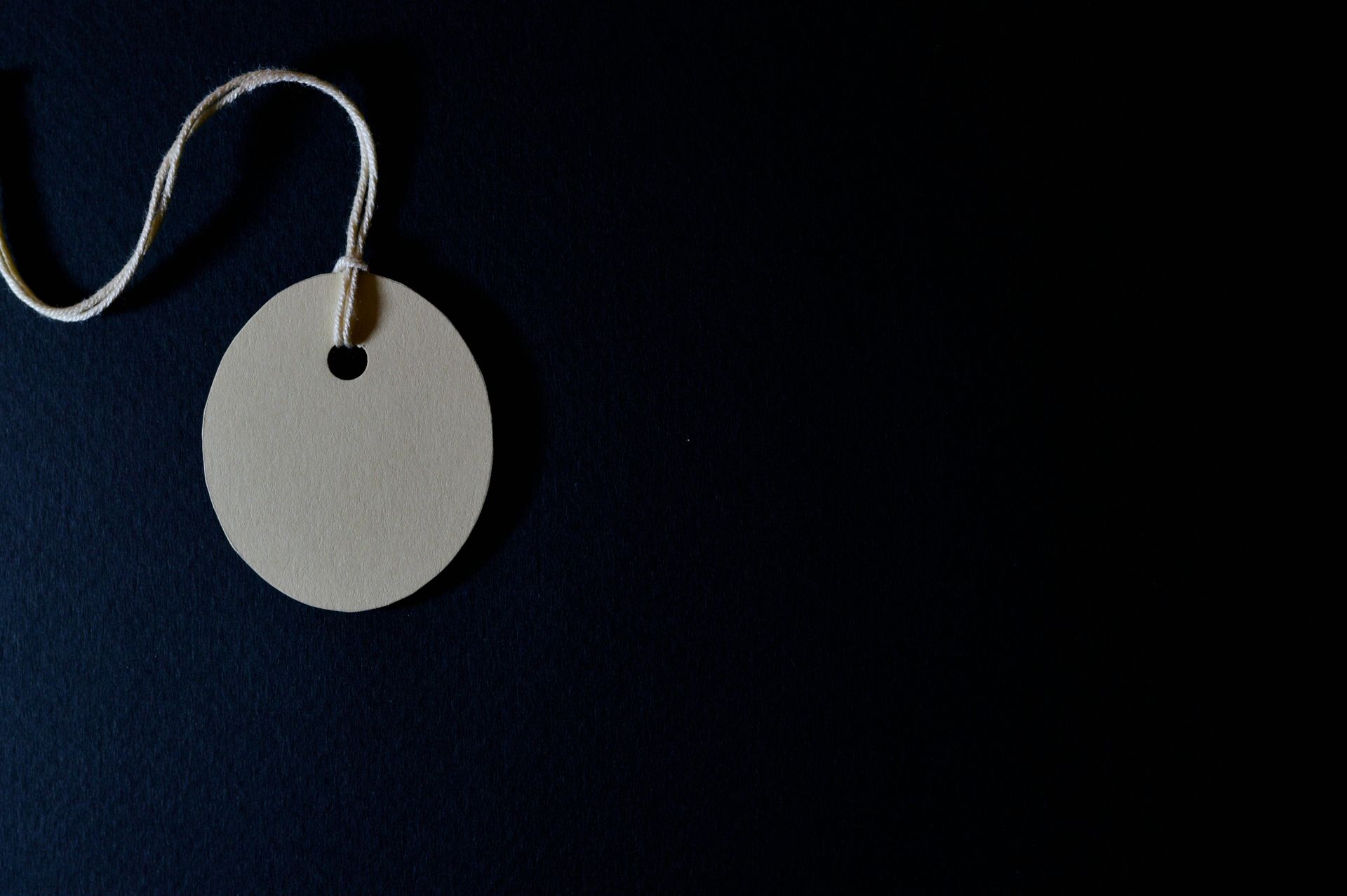 A white tag with a hole in the middle is hanging from a string.