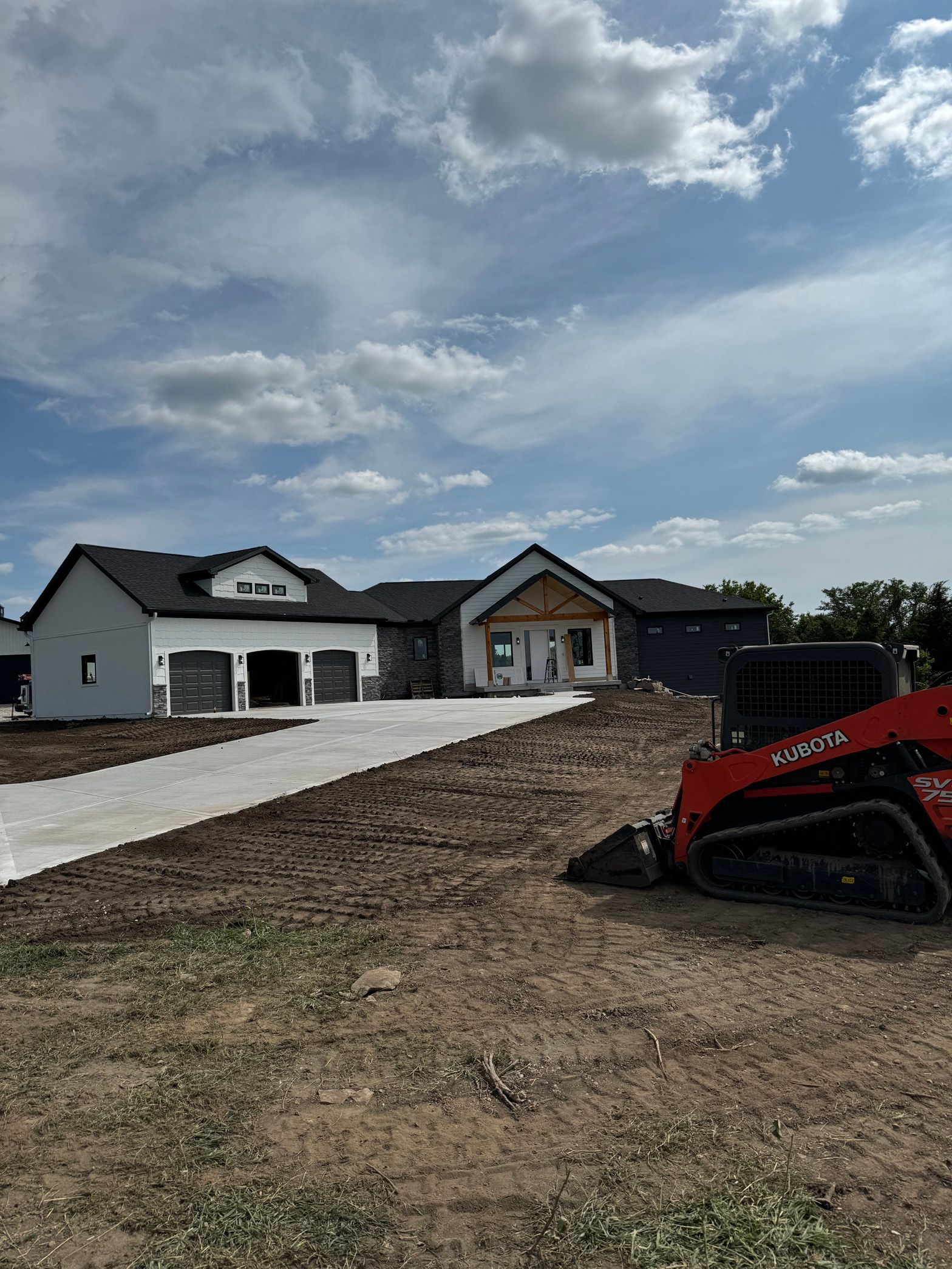 A house is being built and a bulldozer is parked in front of it.