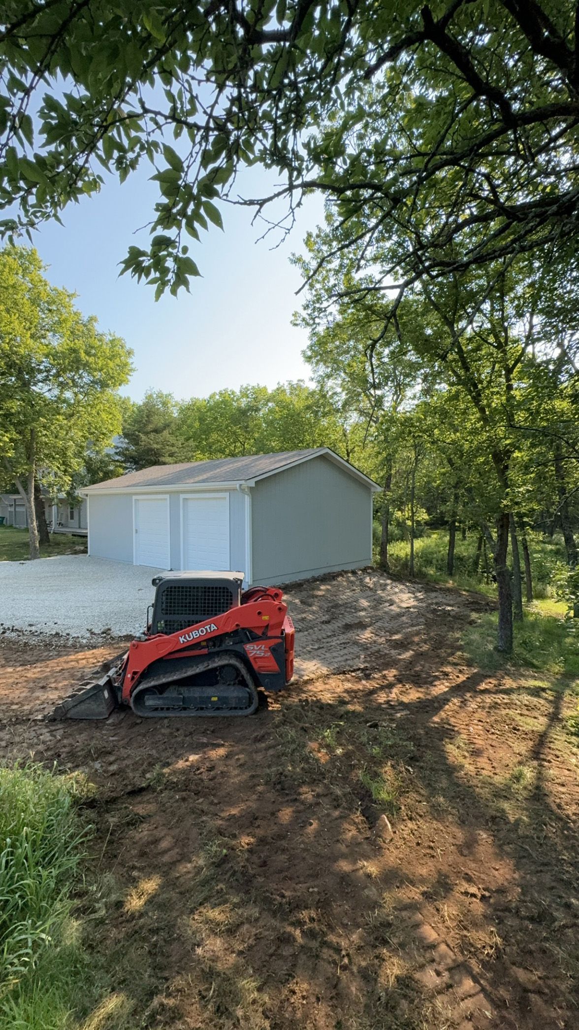A bulldozer is sitting in the dirt in front of a garage.
