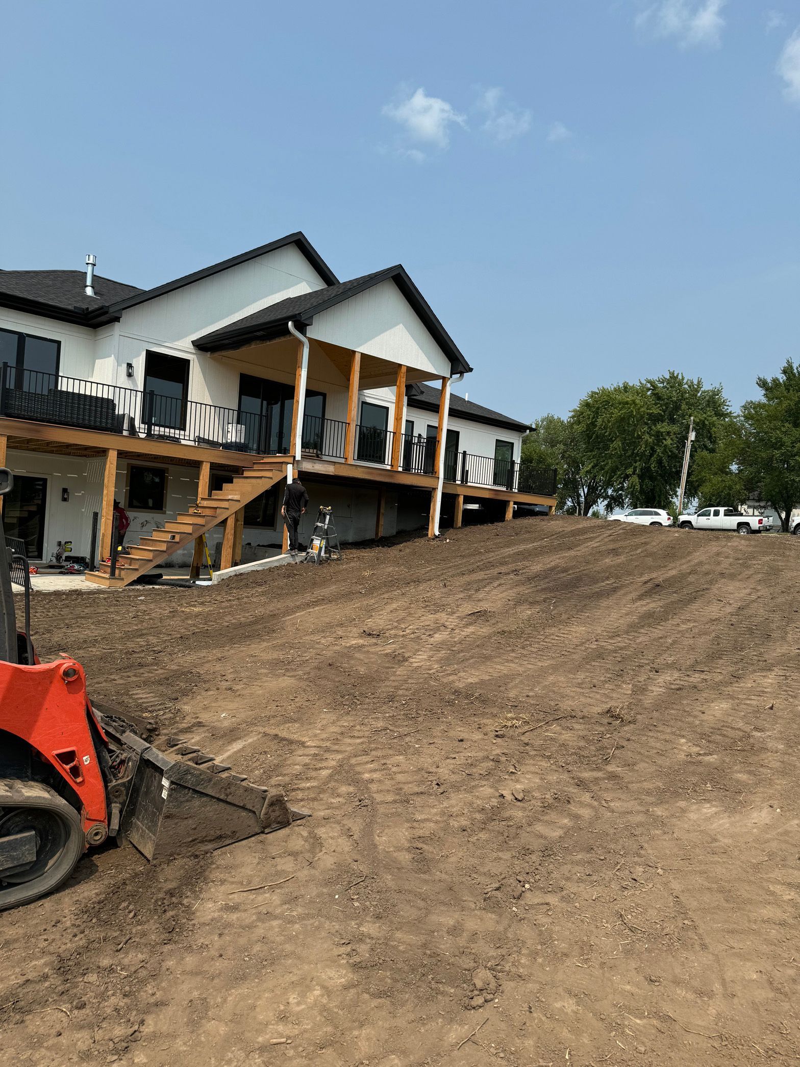 A bulldozer is moving dirt in front of a large house.