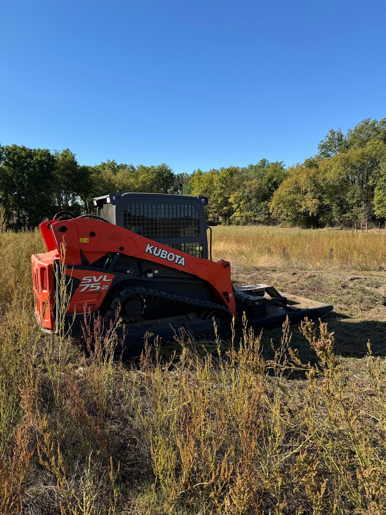 A small orange tractor is sitting in the middle of a field.