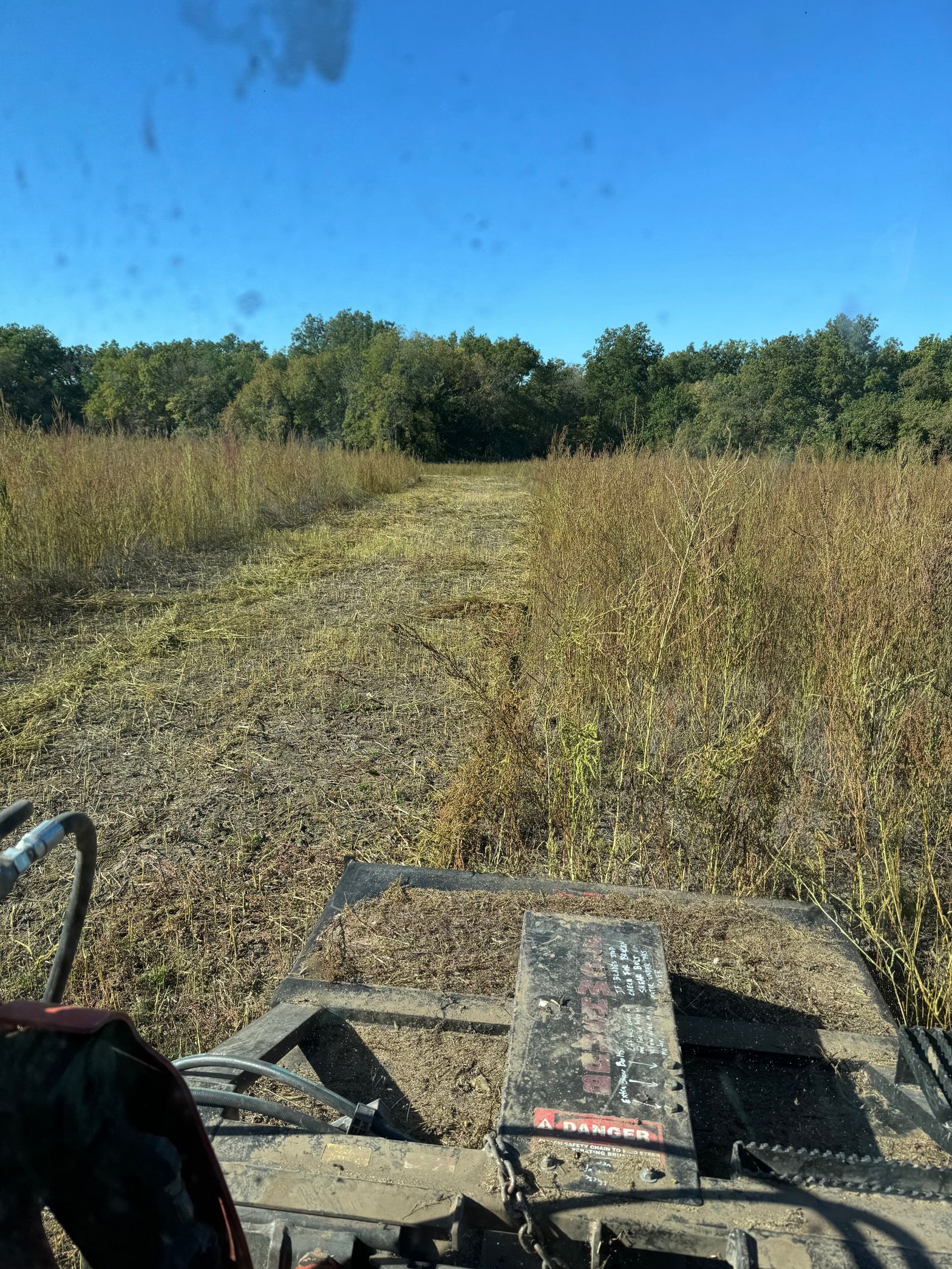 A person is driving a tractor through a field of tall grass.