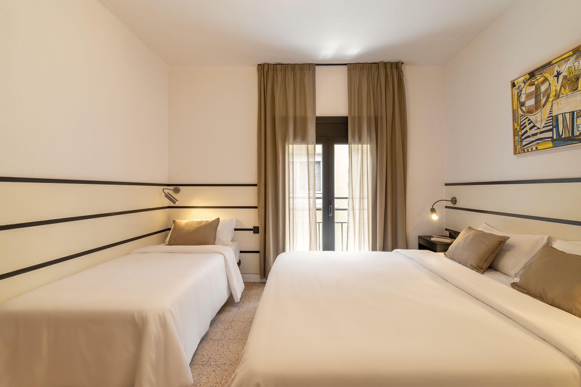 A hotel room with two beds and a large window.