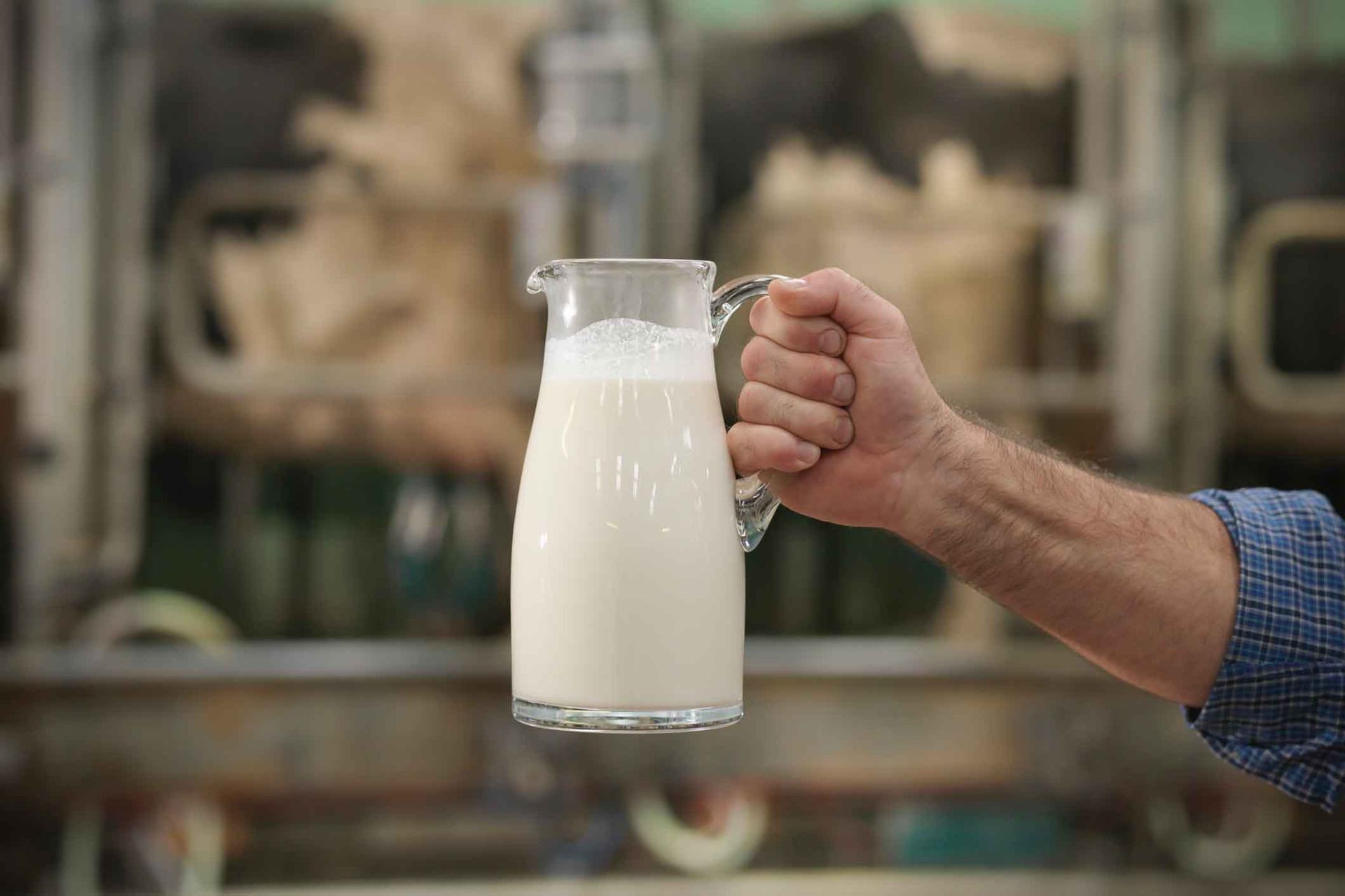A man is holding a pitcher of milk in his hand.