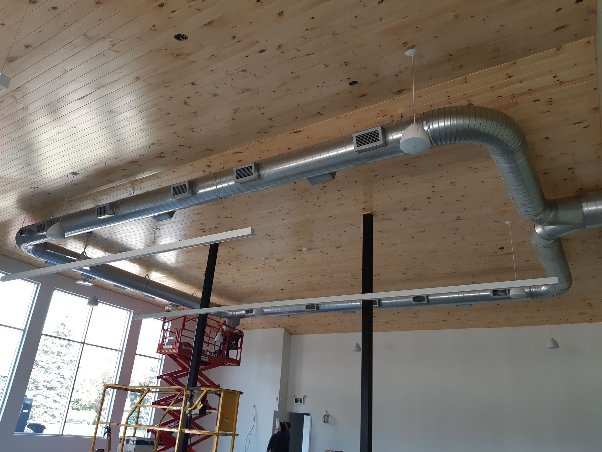 Une pièce avec un plafond en bois et un tuyau en métal suspendu.