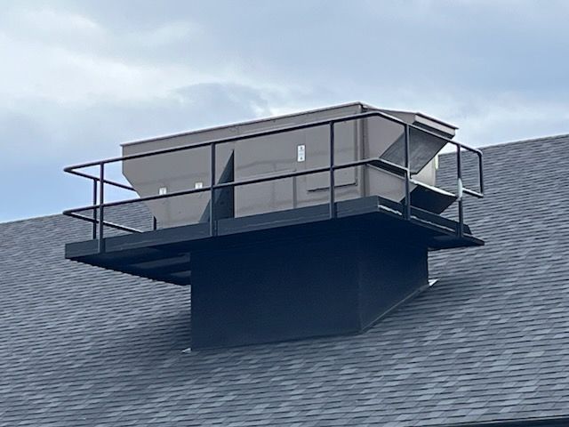 Une grande boîte est posée sur un toit avec une balustrade.