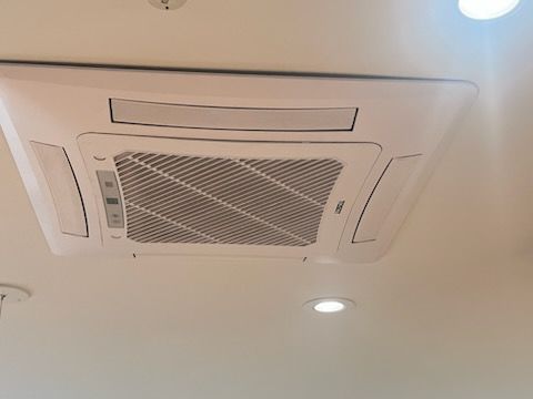 Un climatiseur blanc est suspendu au plafond d'une pièce.