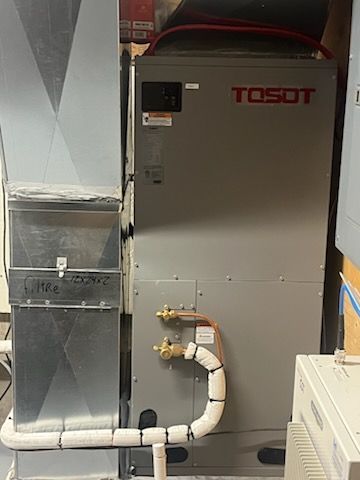 Un climatiseur tosot est placé à côté d'un conduit dans une pièce.