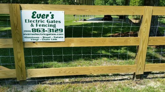 A wooden fence with a sign that says ever 's electric gates and fencing