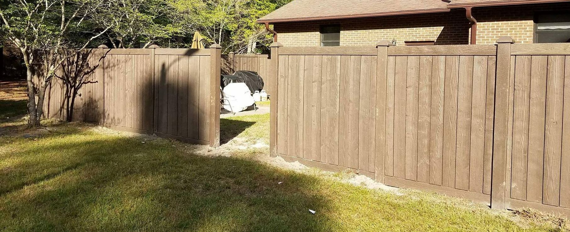 A wooden fence is in the backyard of a house.