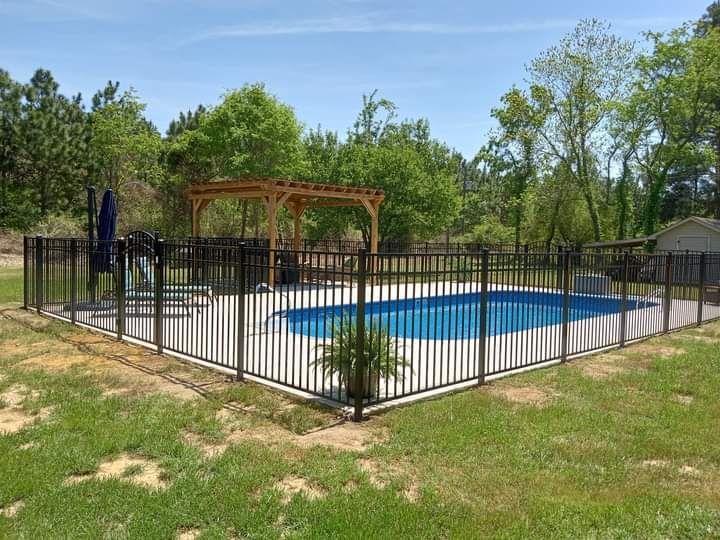 A large swimming pool surrounded by a metal fence and a pergola.
