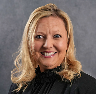 A woman with blonde hair is smiling and wearing a black shirt.