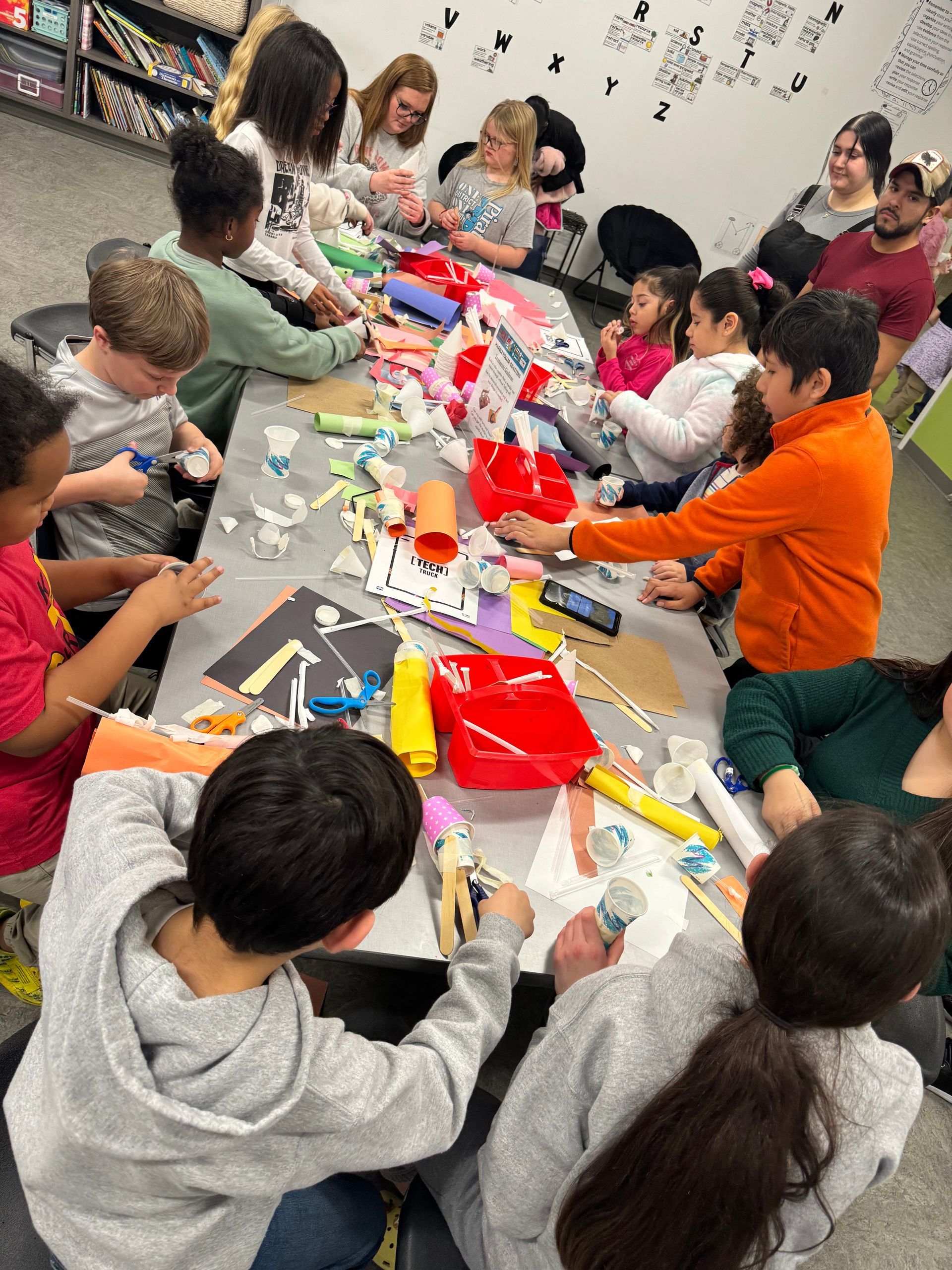 A group of children are sitting around a table making crafts.
