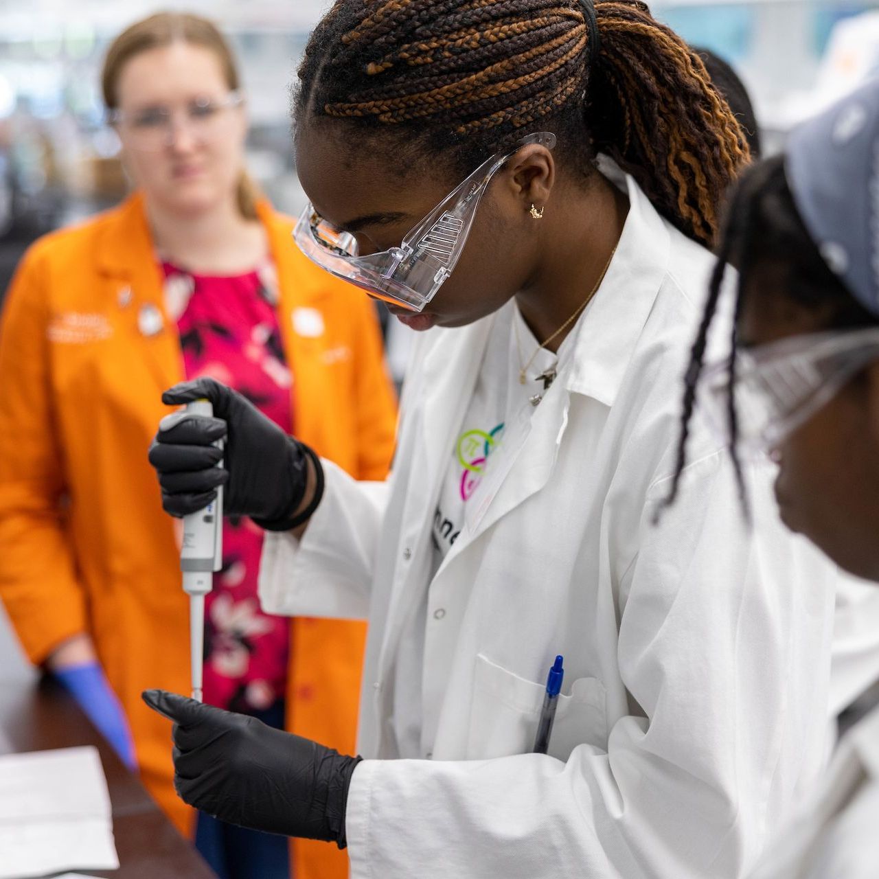 A woman in a lab coat is holding a pipette