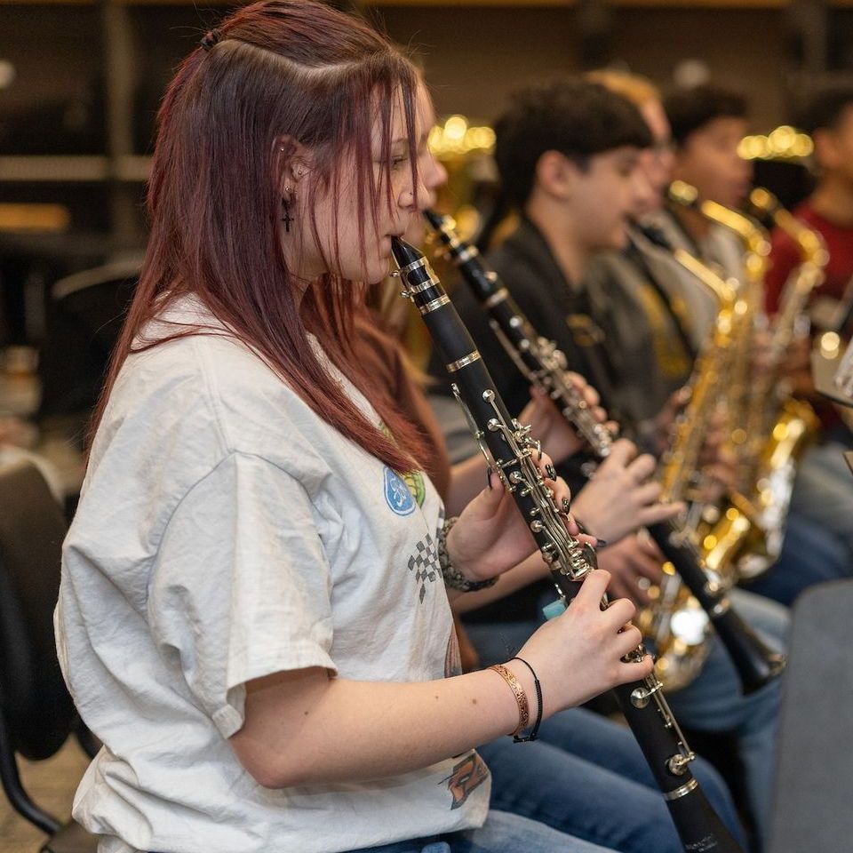 A woman is playing a clarinet in a band