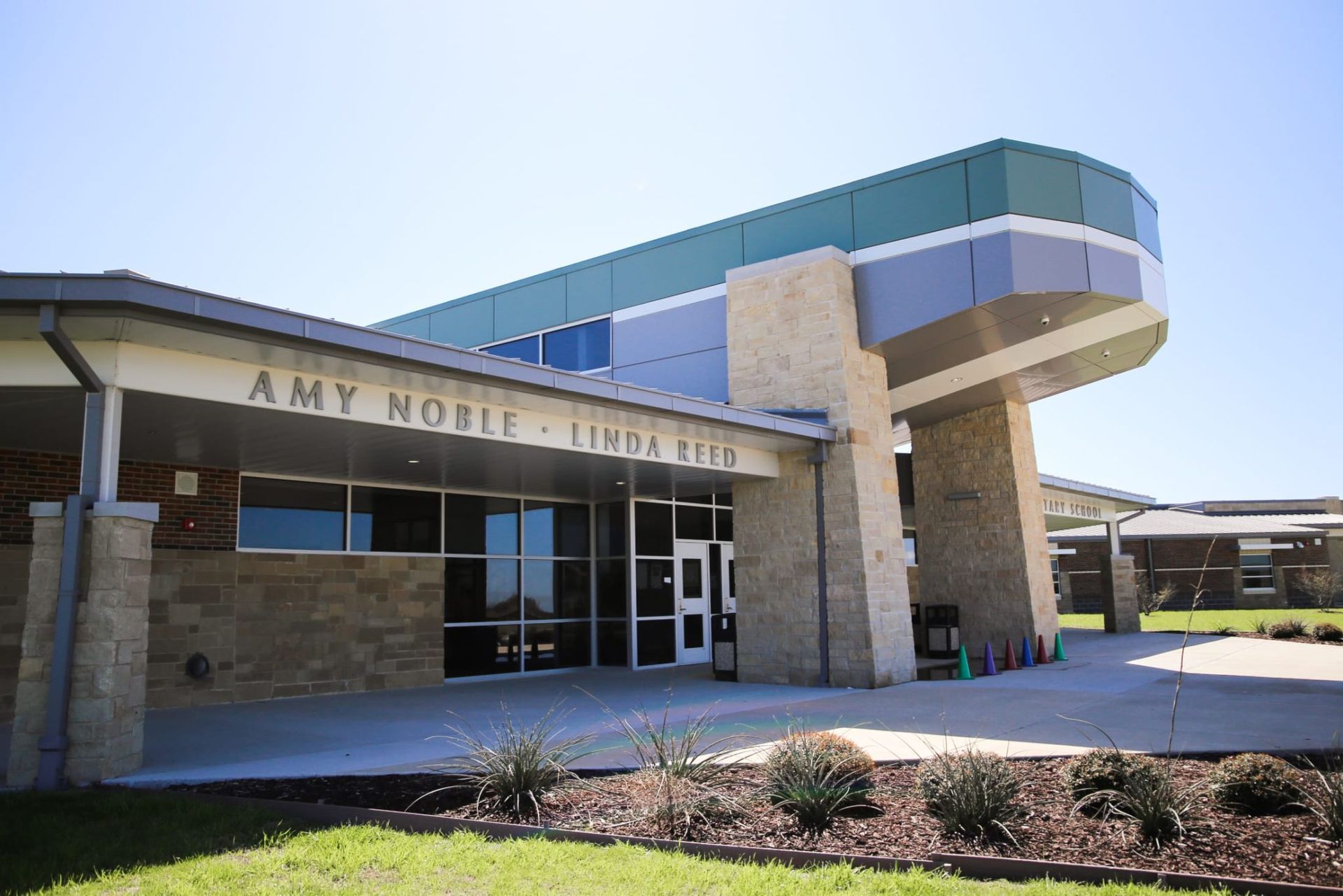 The front of amy middle school is shown on a sunny day.