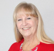 A woman with blonde hair is wearing a red shirt and smiling.