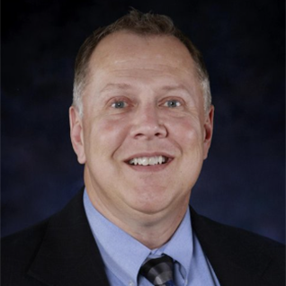 A man in a suit and tie smiles for the camera