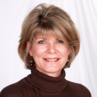 A woman wearing a brown turtleneck smiles for the camera