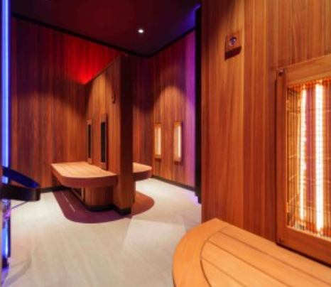 Intérieur de sauna en bois avec bancs, radiateurs infrarouges et éclairage coloré.