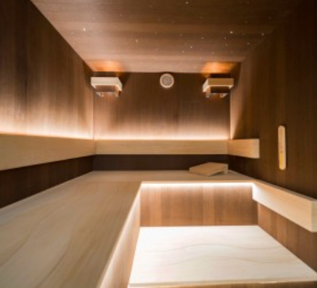 Intérieur d'un sauna en bois avec banquettes et éclairage d'ambiance.