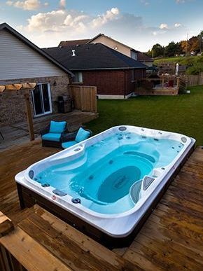 Un spa de nage est posé sur une terrasse en bois dans une cour arrière.