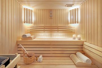 Intérieur de sauna en bois avec bancs, serviettes et seau.