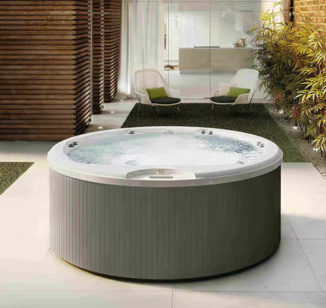 Un bain à remous rond est posé sur une terrasse à côté d'une chaise.