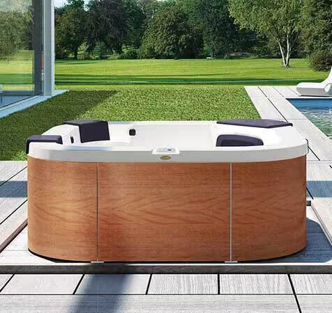 Un bain à remous en bois est posé sur une terrasse en bois à côté d'une piscine.