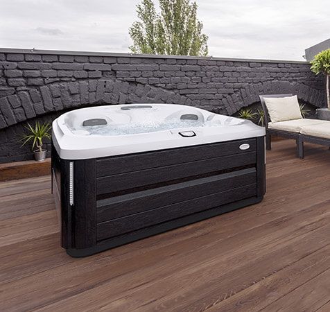 Un bain à remous noir et blanc est posé sur une terrasse en bois.