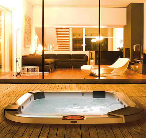 Un bain à remous est installé sur une terrasse en bois devant un salon.