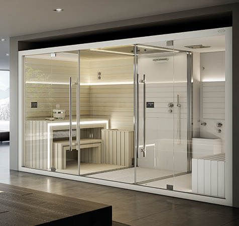 Spa moderne avec parois vitrées, comprenant un sauna, une douche et des banquettes ; couleurs neutres et éclairage d'ambiance.