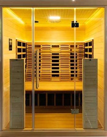 Un sauna avec une porte vitrée et une lumière jaune au plafond.