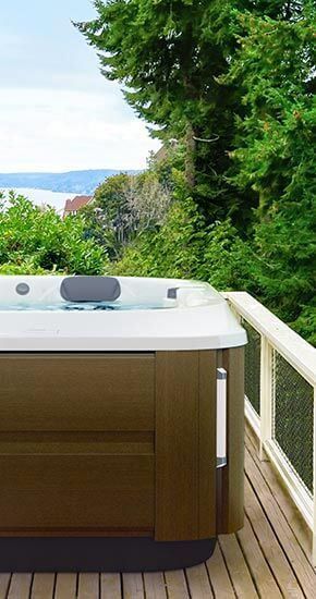 Un bain à remous est installé sur une terrasse en bois surplombant l'océan.