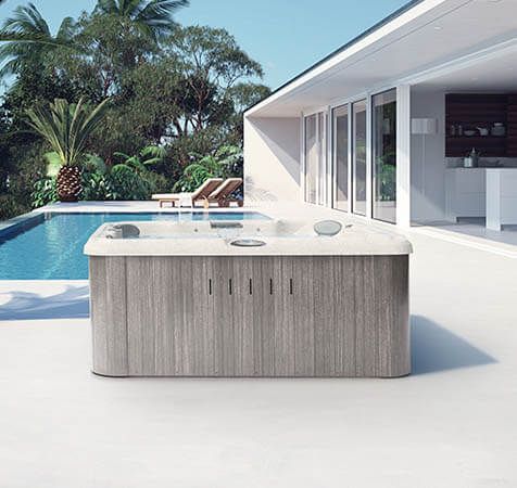 Un bain à remous est installé sur une terrasse à côté d'une piscine.