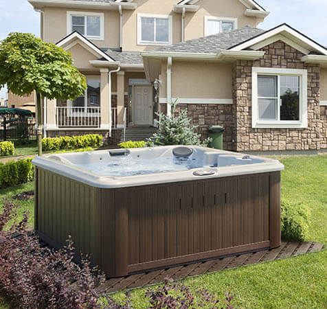 Une grande maison avec un jacuzzi devant